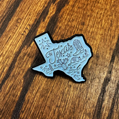 White Texas-shaped pin on a wooden surface