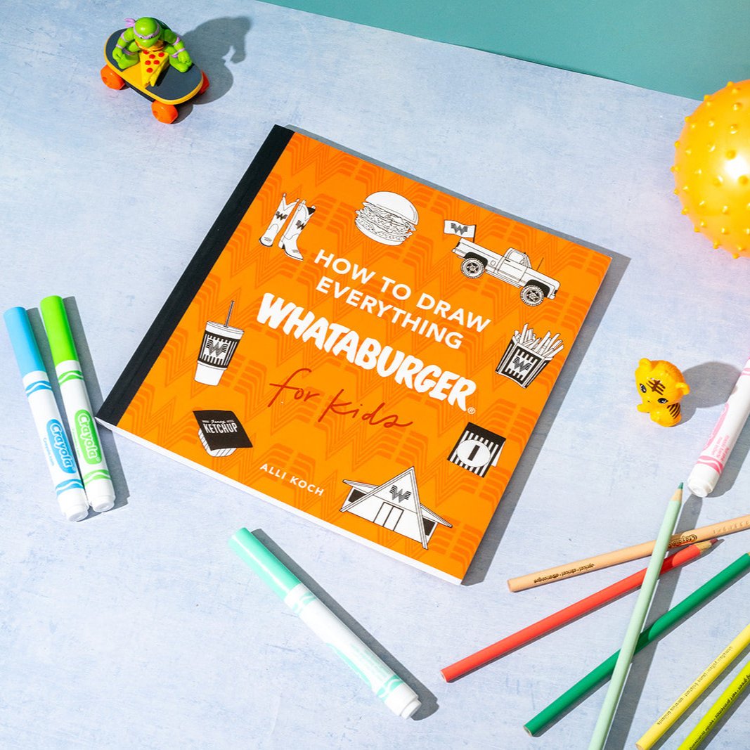 Book titled 'How to Draw Everything Whataburger for Kids' on a light blue surface with drawing tools.