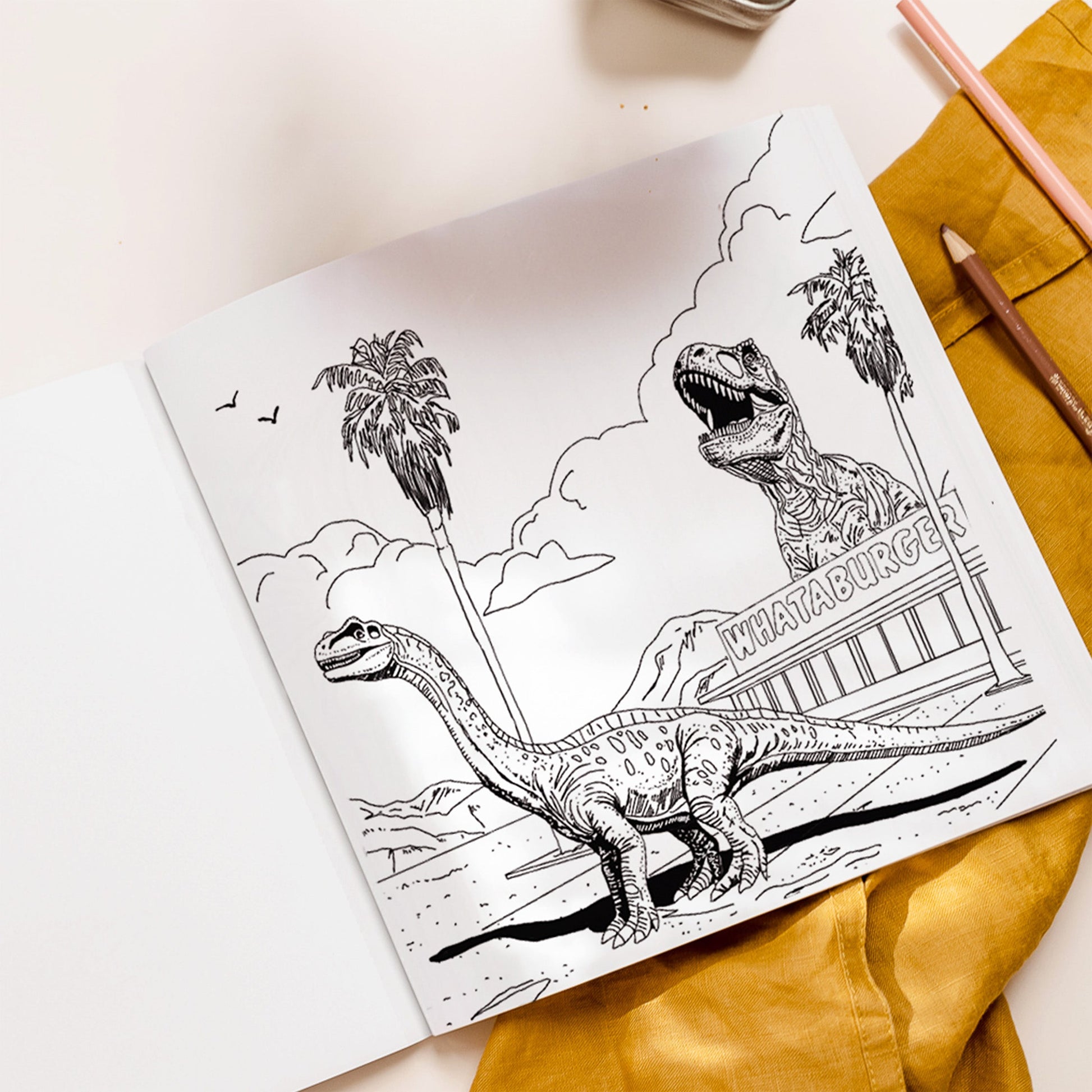 Coloring book with dinosaur illustrations on a white surface with a yellow notebook and pen and Whataburger